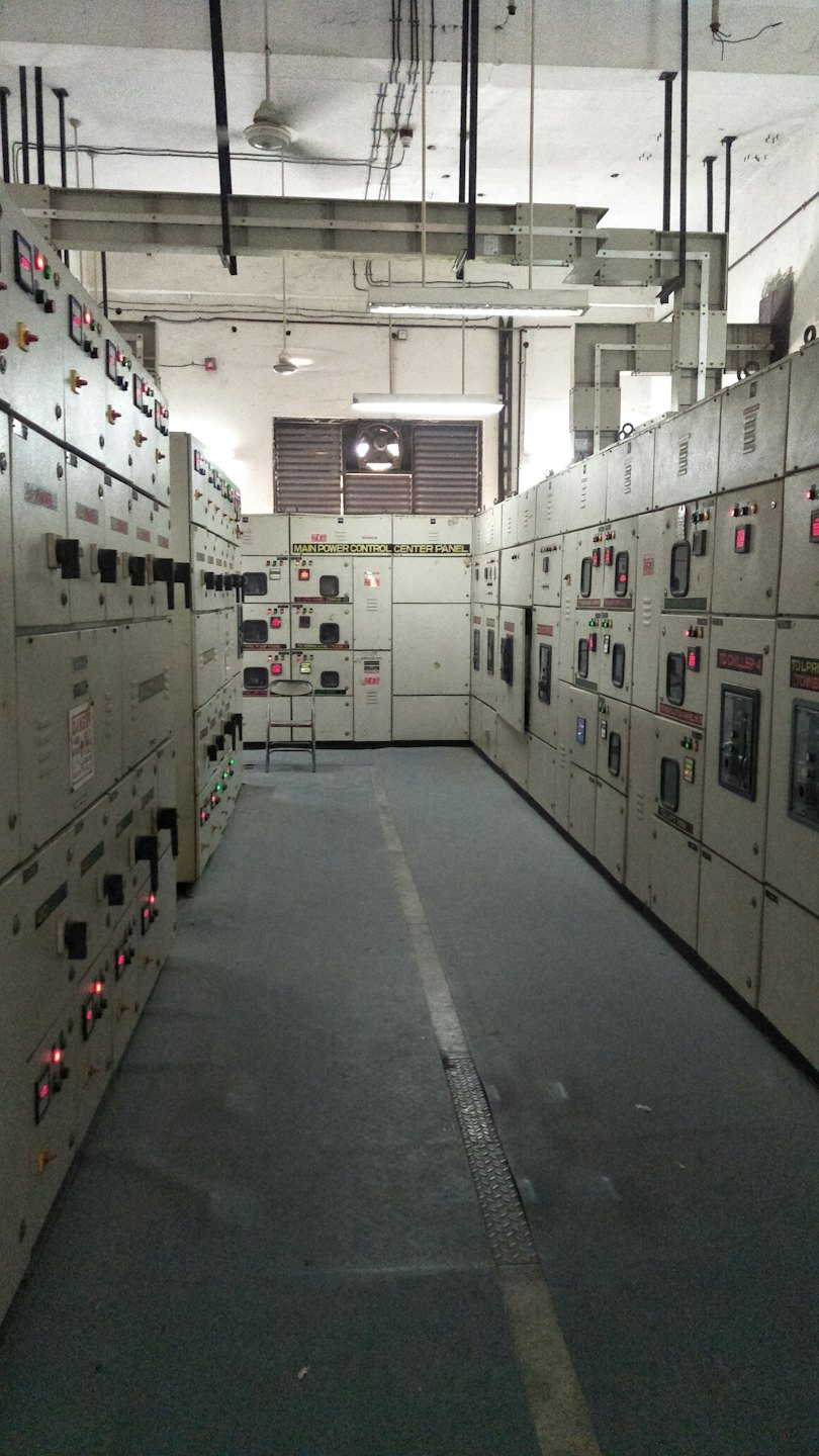 Corredor industrial con paneles de control eléctrico y centro de energía principal.