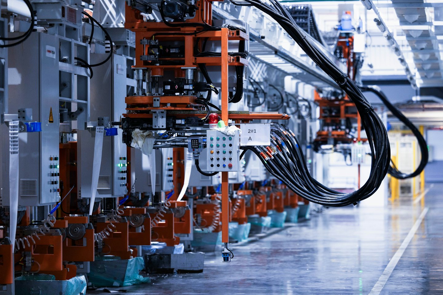 Maquinaria industrial automatizada con componentes naranjas y grises en una fábrica.