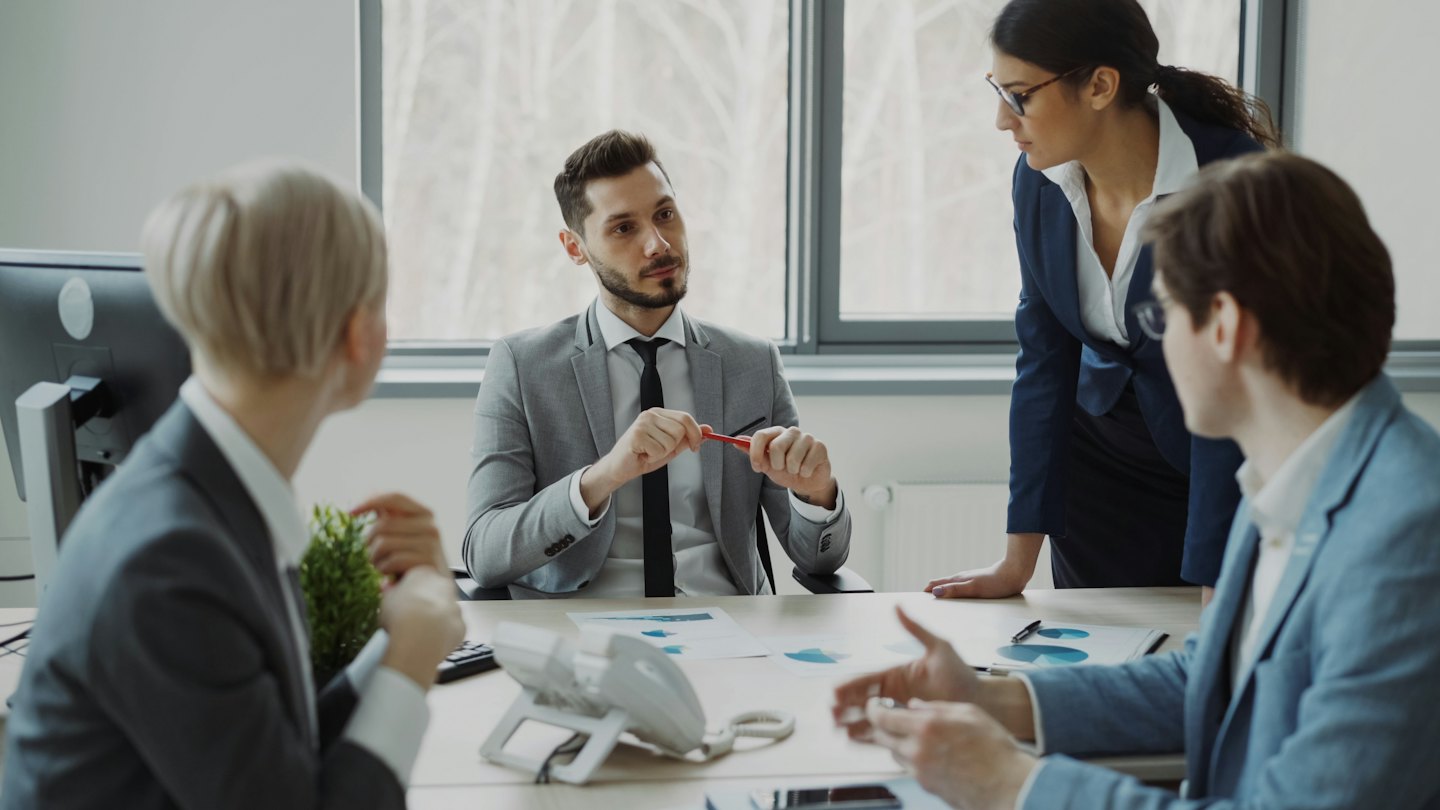 Profesionales de negocios discuten planes alrededor de una mesa de conferencias.
